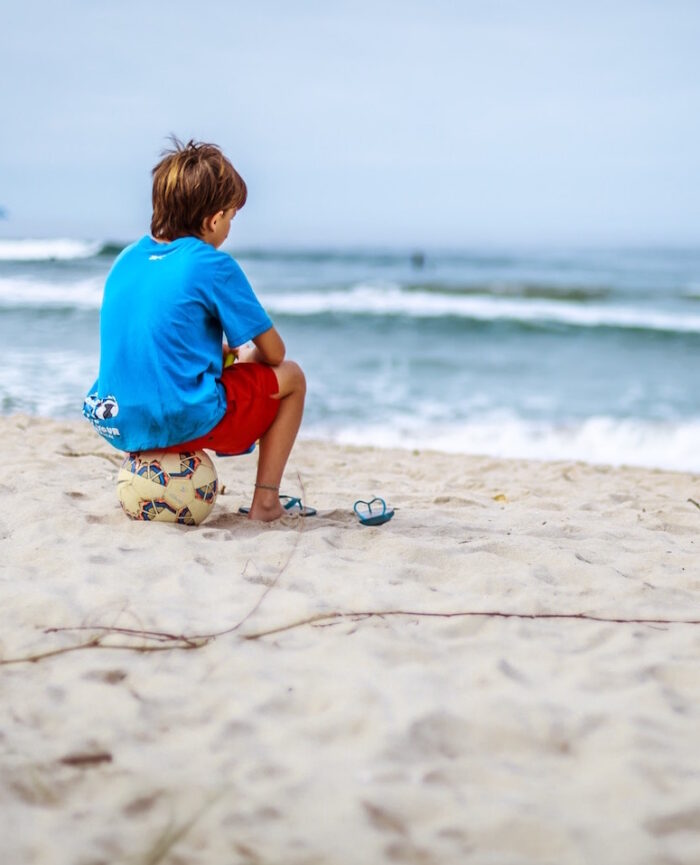 kid on soccer ball in sand