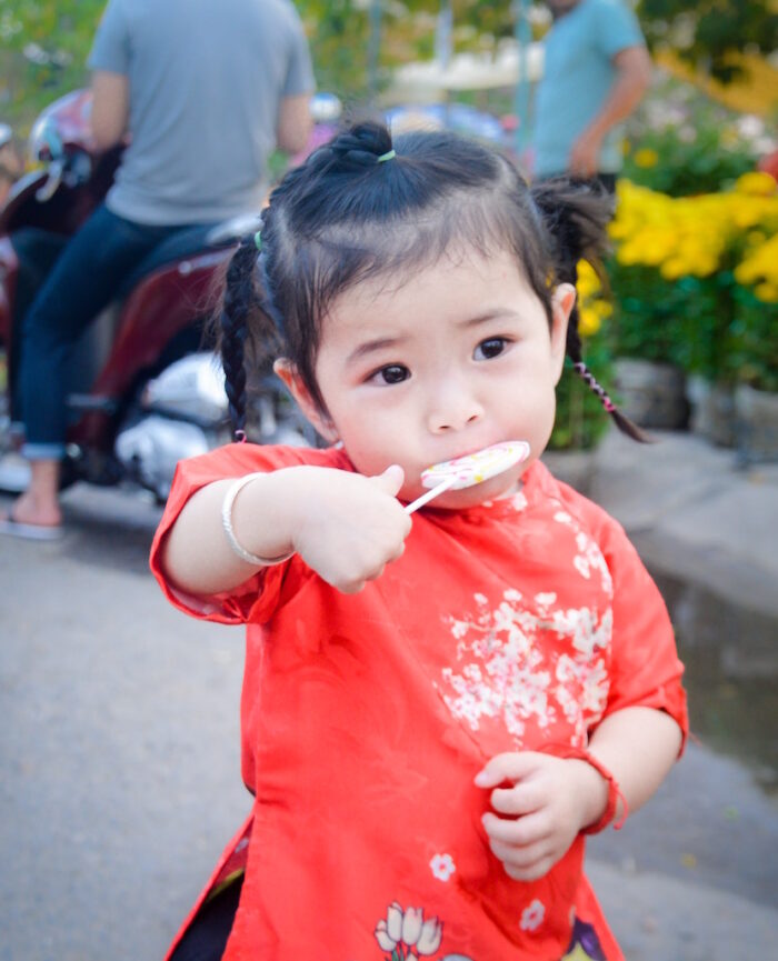 little girl with braids enjoying lollipop